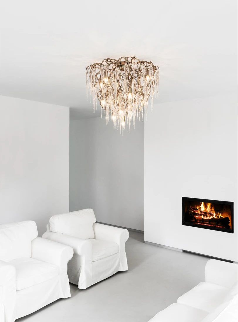 In einem weißen Raum mit weißen Sesseln und brennendem Kaminfeuer hängt der Leuchter 'Hollywood Icicles' von Brand van Egmond.