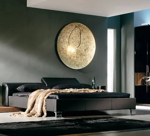 Ein schwarzes Bett mit einer braunen Felldecke, darüber an der Kopfwand die Leuchte 'Luna Piena' von Catellani & Smith.