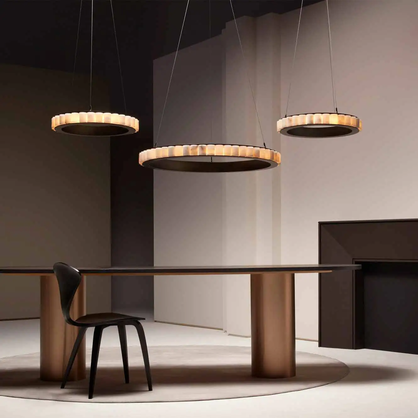 Über einem großen Tisch mit einem Stuhl davor hängen drei Leuchter 'Avalon' von CTO Lighting.